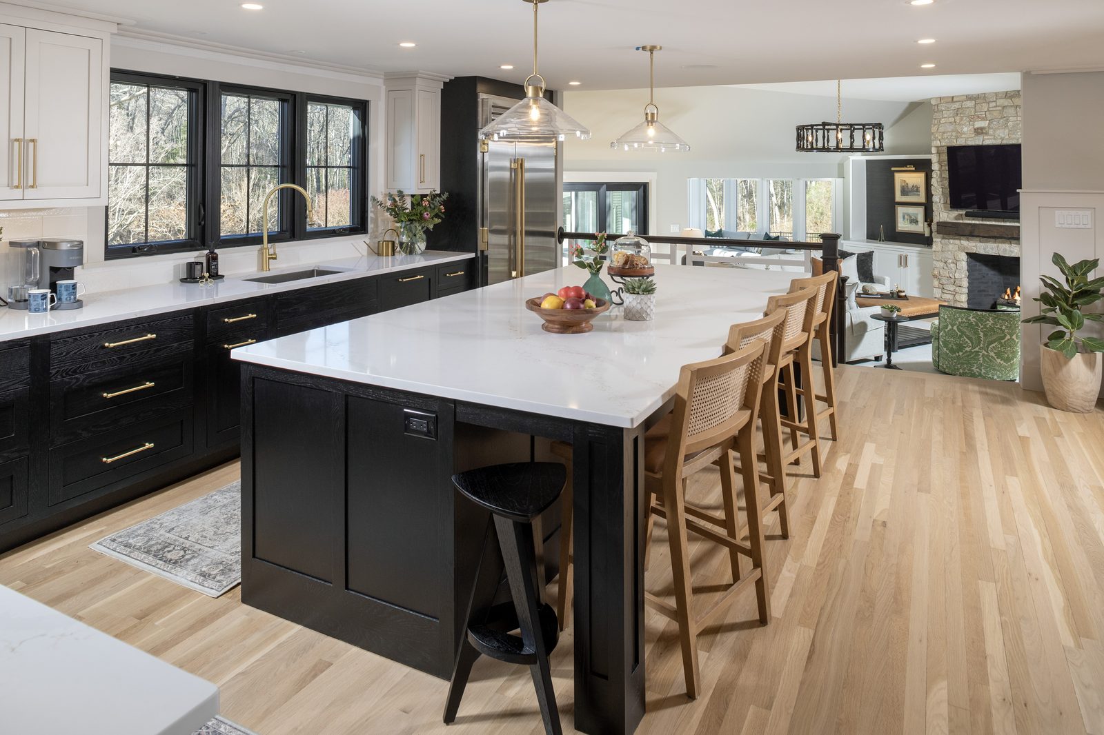 Kitchen island with wood seating opening to a living room with a stone fireplace