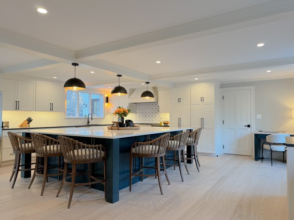 White kitchen with dark island cabinetry and pendant lighting