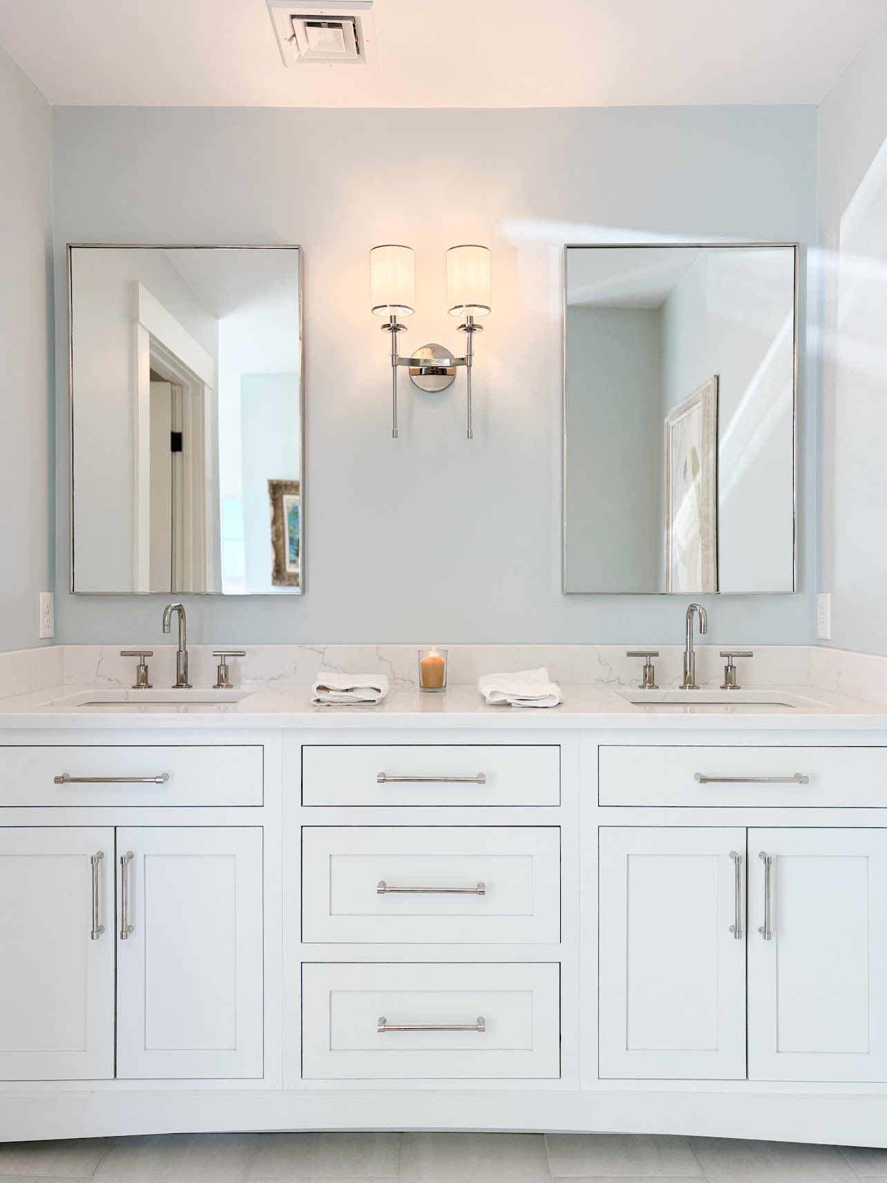White double bathroom vanity with pale blue walls and polished metal fixtures