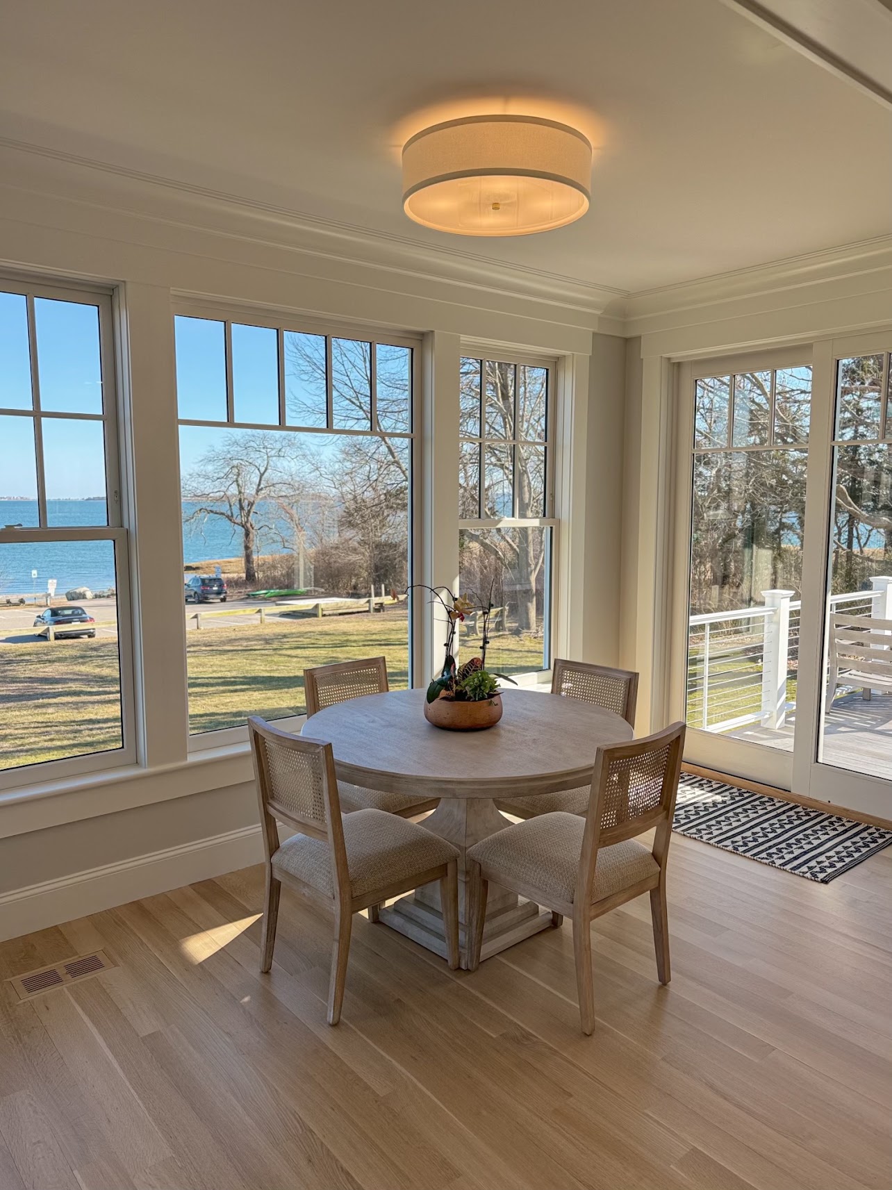 Breakfast nook with a round table, wide ocean-facing windows, and a door to the deck