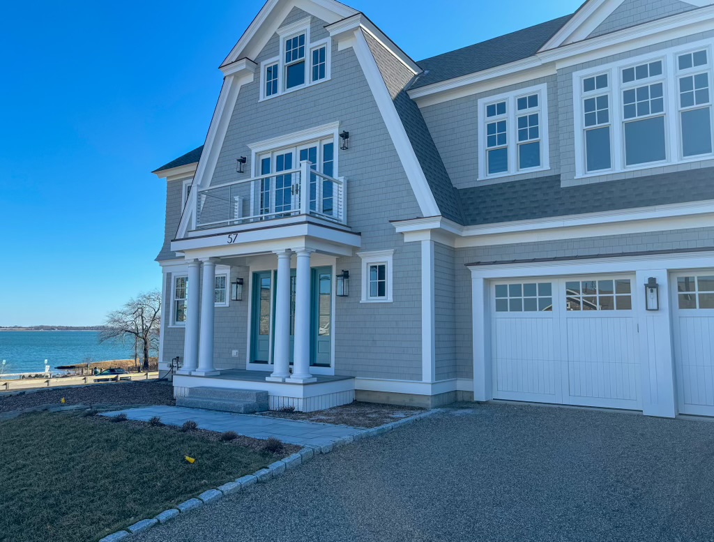 Gray shingle oceanfront home with white trim, a balcony, and garage