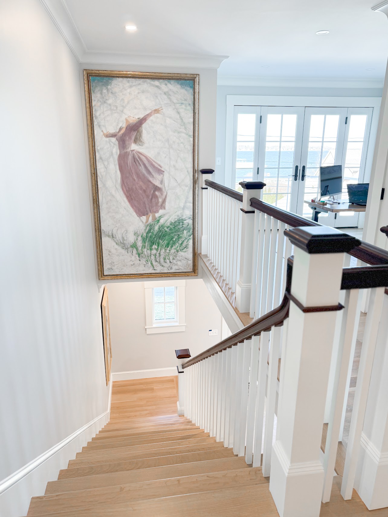 Wood staircase with white balusters and dark handrails leading to an ocean-facing landing