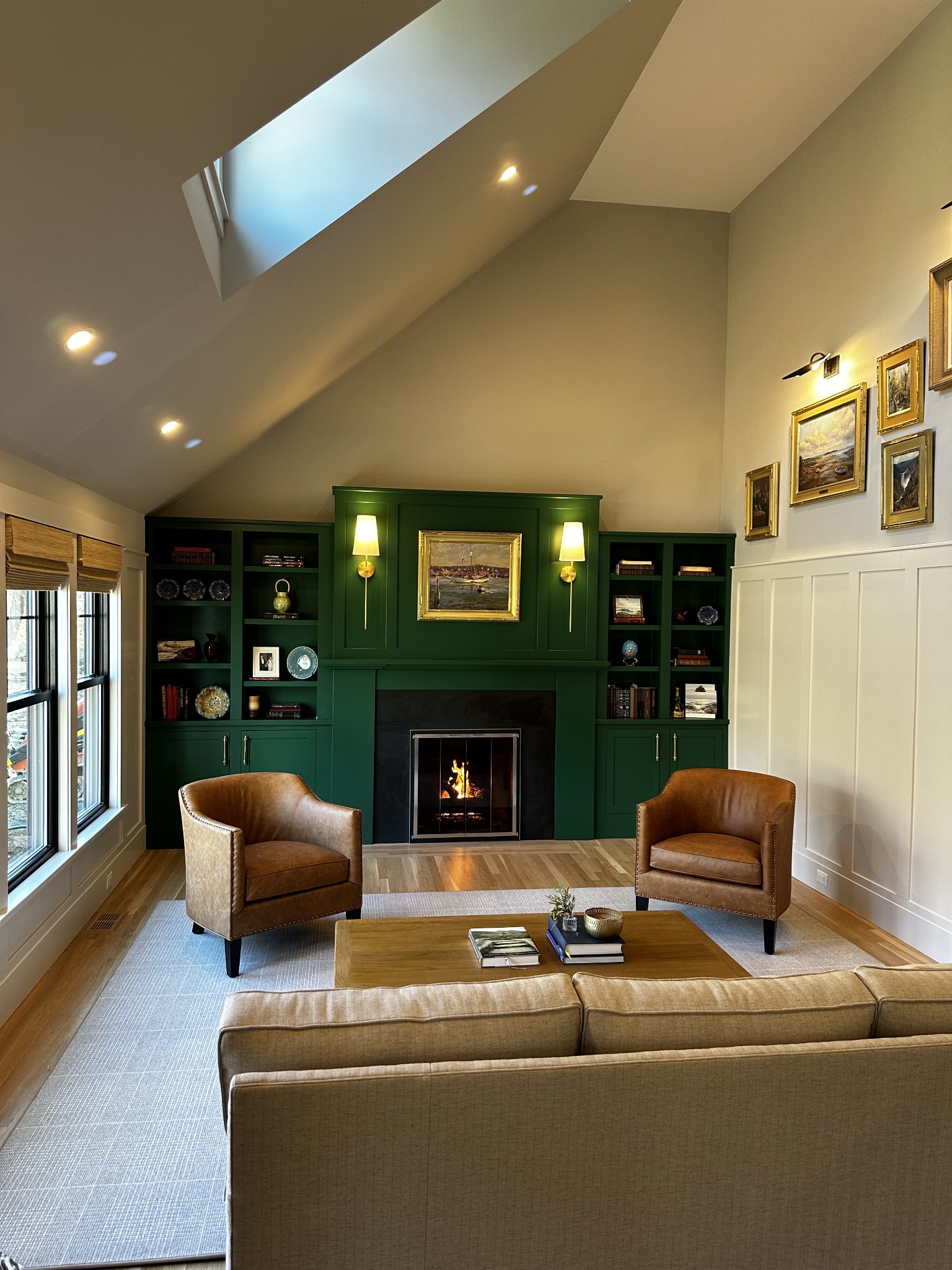 Sitting room with a vaulted ceiling, skylight, green built-in cabinetry, and fireplace