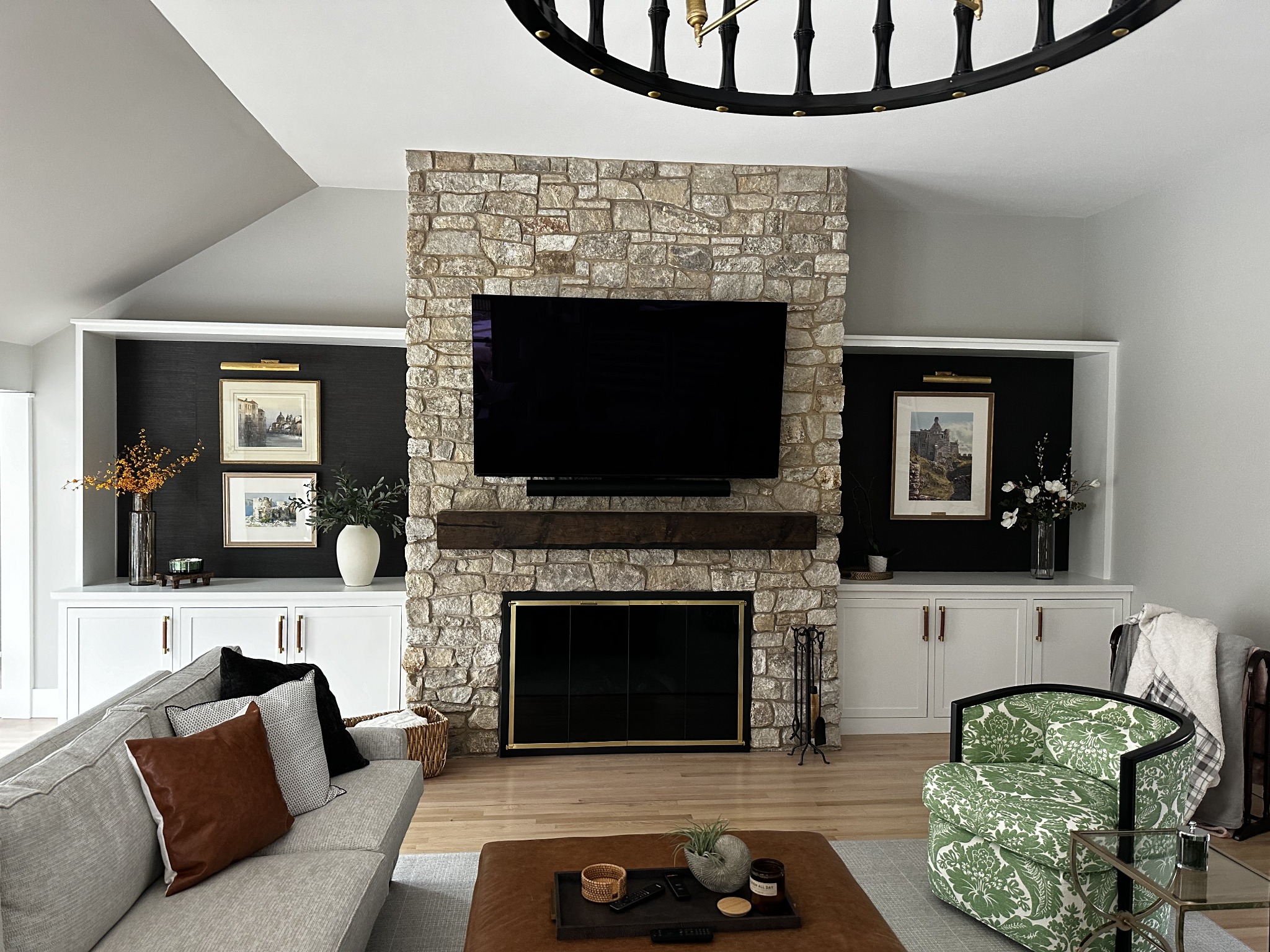 Living room with a stone fireplace, wood mantel, and white built-in cabinetry